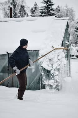 man removing snow from a house roof